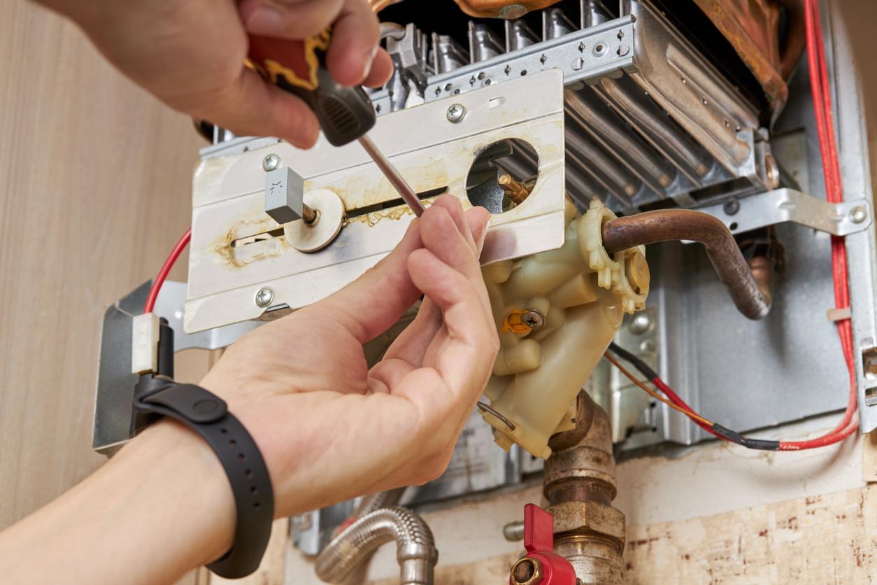 Plumber uses a screwdriver during a water heater service call