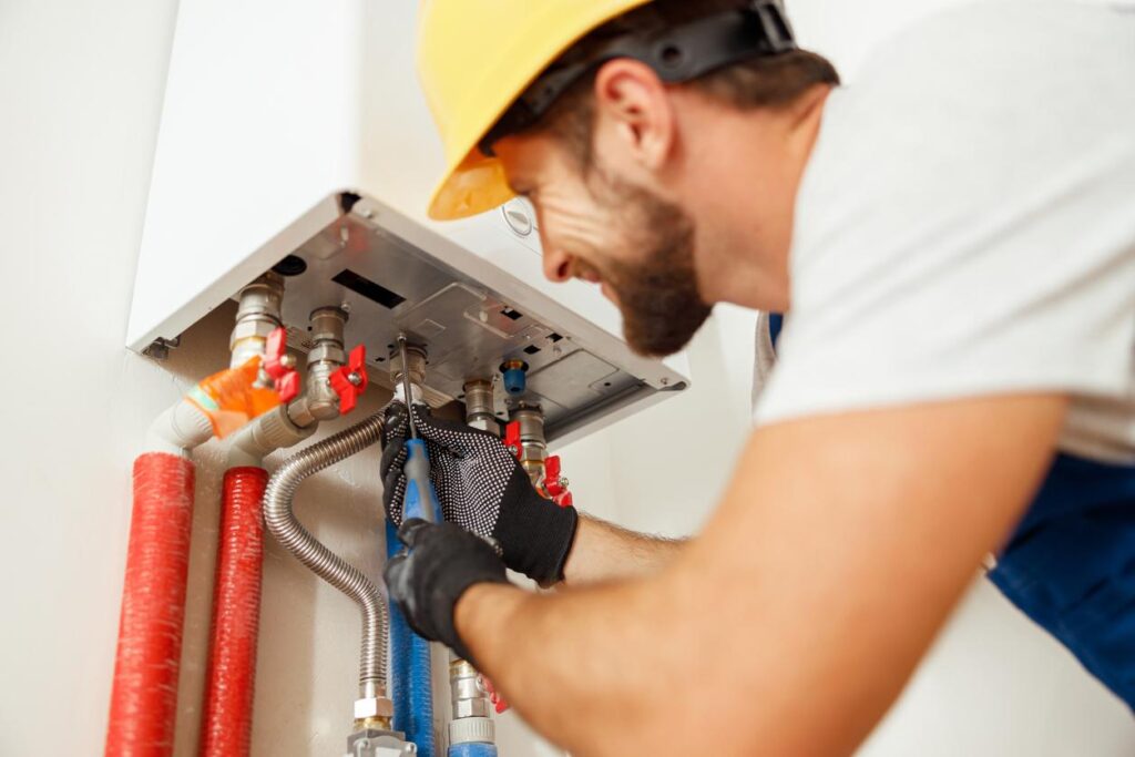 Plumber uses screwdriver to repair water heater